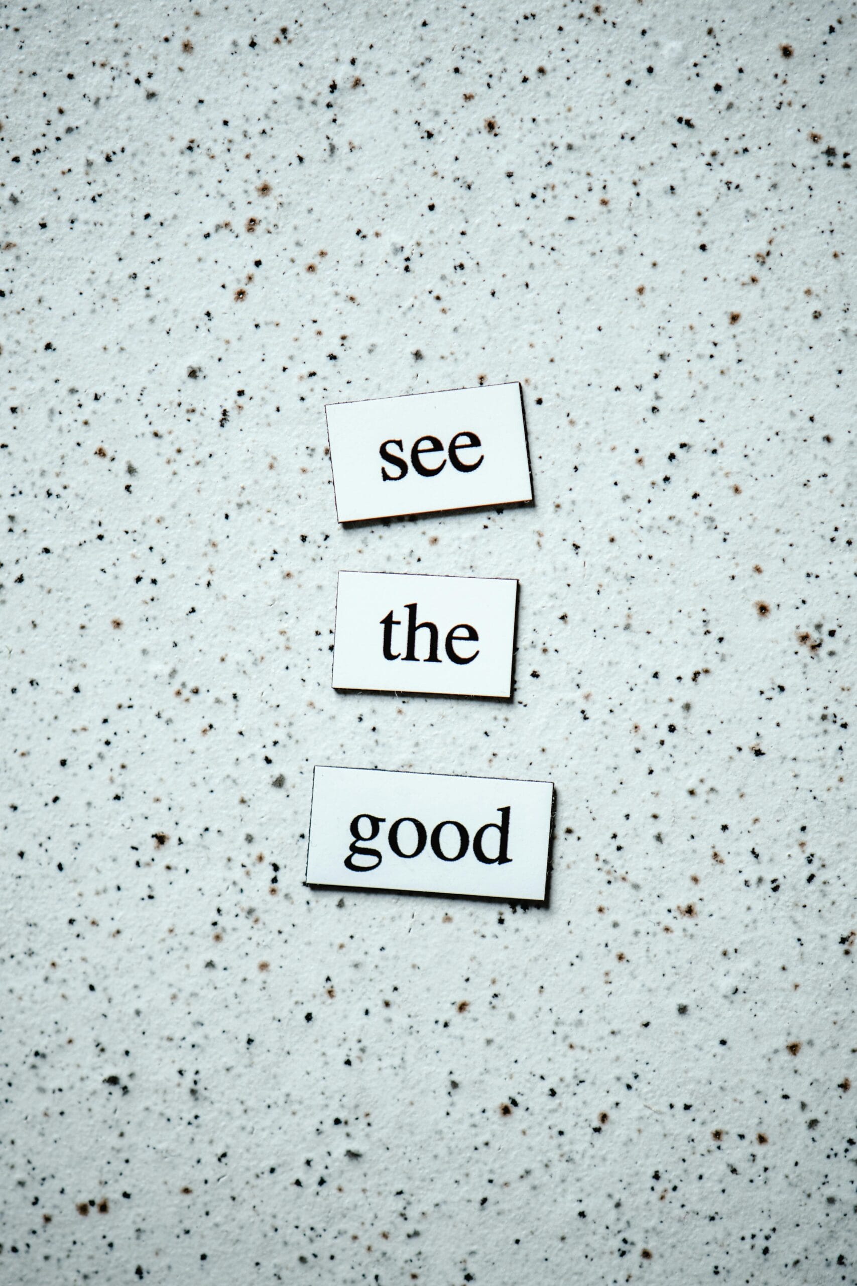 Inspiring words 'See the Good' displayed on a speckled backdrop.